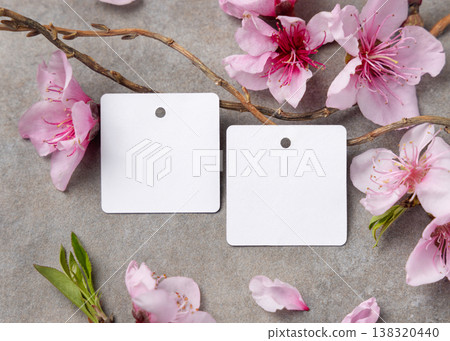 Blank square gift tags mockup with pink spring flowers and wooden twigs on grey stone, label design 138320440