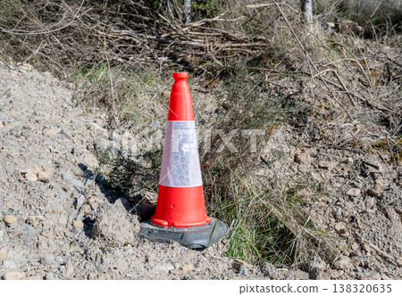 Bright orange traffic cone on roadside construction area safety warning equipment in outdoor environment 138320635