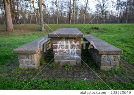 Stone picnic table with benches in park landscape outdoor public seating with graffiti on concrete structure Stone picnic table with benches in park landscape outdoor public seating with graffiti on concrete structure 138320649
