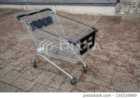 Abandoned shopping cart on urban street pavement empty supermarket trolley in city environment consumerism concept Abandoned shopping cart on urban street pavement empty supermarket trolley in city environment consumerism concept 138320660