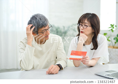 A couple in their 60s looking at their savings passbook in the living room 138321487