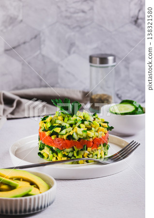 Diet salad with avocado, cucumber and red fish on a plate on the table vertical view Diet salad with avocado, cucumber and red fish on a plate on the table vertical view 138321580