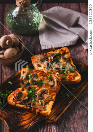 Hot toasts with mushrooms, cheese and herbs on a board on the table vertical view Hot toasts with mushrooms, cheese and herbs on a board on the table vertical view 138321590