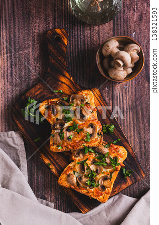 Hot toasts with mushrooms, cheese and herbs on a board on the table top and vertical view Hot toasts with mushrooms, cheese and herbs on a board on the table top and vertical view 138321593