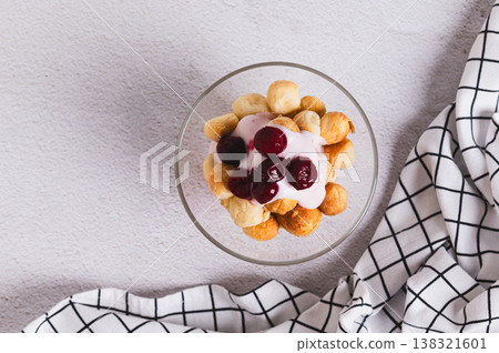 Close up of small round cookies, yogurt and cherry jam in bowls on the table top view Close up of small round cookies, yogurt and cherry jam in bowls on the table top view 138321601