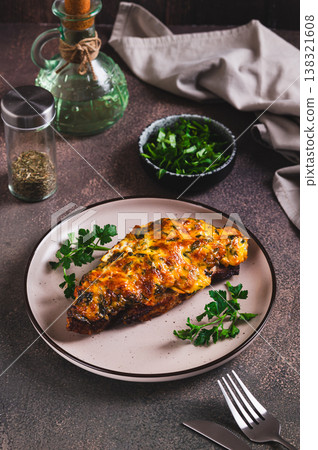 Appetizing meat baked under a cheese crust on a plate on the table vertical view 138321608