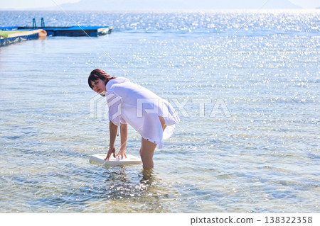 A woman places a chair in the sea for a photo shoot A woman places a chair in the sea for a photo shoot 138322358