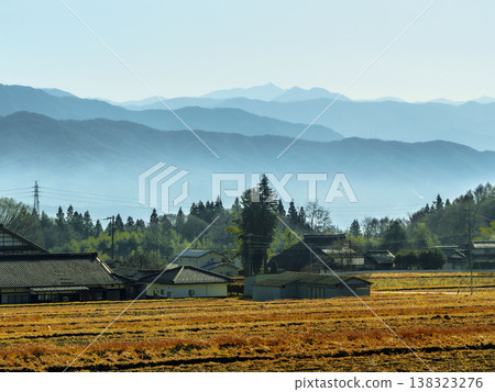 A tranquil landscape unfolds, with the still earthy winter rice fields stretching out against the backdrop of distant, misty mountains. A tranquil landscape unfolds, with the still earthy winter rice fields stretching out against the backdrop of distant, misty mountains. 138323276