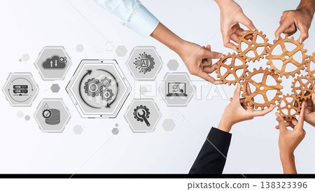 Hands unite to hold wooden gears, representing teamwork and innovation amidst digital icons in a modern workspace, showcasing collaboration and technological synergy. Sigmoid 138323396