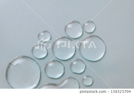 Transparent gel and serum drops on pale blue background, moisturizing skincare and dermatological product texture Transparent gel and serum drops on pale blue background, moisturizing skincare and dermatological product texture 138323704