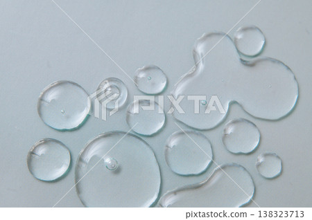 Transparent gel and serum drops on pale blue background, moisturizing skincare and dermatological product texture Transparent gel and serum drops on pale blue background, moisturizing skincare and dermatological product texture 138323713