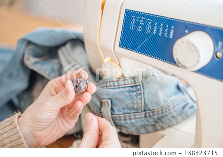 Woman sewing denim on sewing machine at home, handmade clothing and tailoring concept Woman sewing denim on sewing machine at home, handmade clothing and tailoring concept 138323715