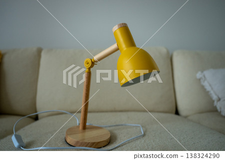 Modern yellow desk lamp with wooden base on sofa minimal home interior lighting design concept Modern yellow desk lamp with wooden base on sofa minimal home interior lighting design concept 138324290