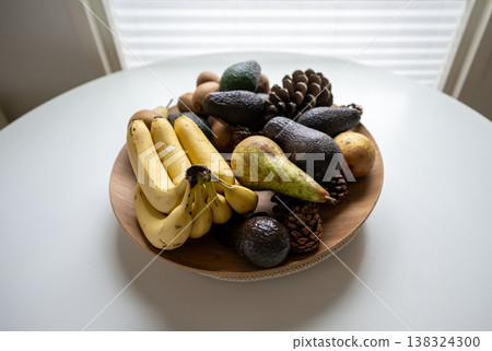 Fresh fruit bowl with banana avocado pear and natural organic ingredients on table healthy eating concept minimal kitchen scene Fresh fruit bowl with banana avocado pear and natural organic ingredients on table healthy eating concept minimal kitchen scene 138324300