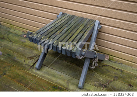 Old wooden folding stool with moss on rustic terrace weathered outdoor furniture texture and decay concept 138324308