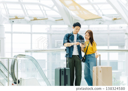 A couple looking at their smartphones at a shopping mall while traveling. (Photo courtesy of Kansai International Airport (KIX)) A couple looking at their smartphones at a shopping mall while traveling. (Photo courtesy of Kansai International Airport (KIX)) 138324580