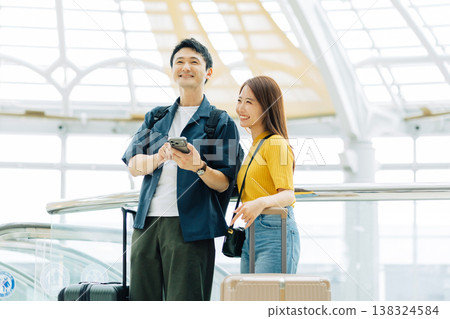 A couple looking at their smartphones at a shopping mall while traveling. (Photo courtesy of Kansai International Airport (KIX)) A couple looking at their smartphones at a shopping mall while traveling. (Photo courtesy of Kansai International Airport (KIX)) 138324584