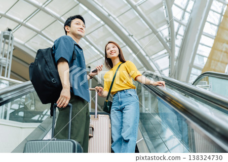 A couple looking at their smartphones on an escalator at a travel destination. (Photo courtesy of Kansai International Airport (KIX)) 138324730