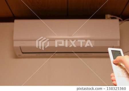 Hand to operate the remote control of the air conditioner Hand to operate the remote control of the air conditioner 138325360