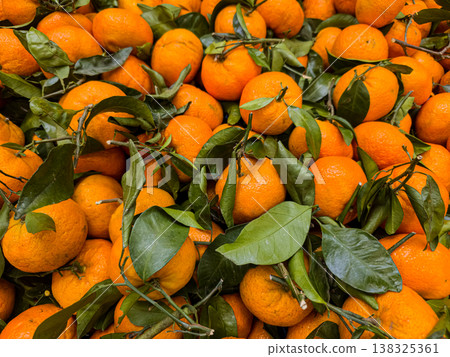 Vibrant background pattern of fresh organic mandarins with green leaves at market Vibrant background pattern of fresh organic mandarins with green leaves at market 138325361