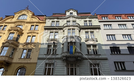 Old buildings stand side by side on a street in Prague with clear blue skies above during the day Old buildings stand side by side on a street in Prague with clear blue skies above during the day 138326023