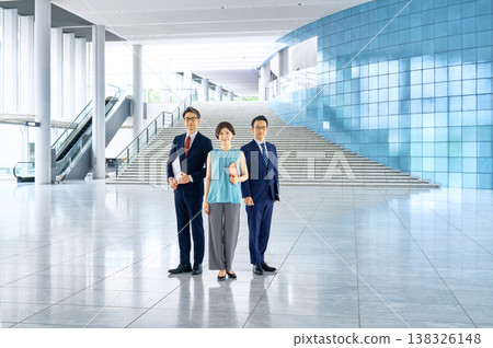 一群商務團隊成員面帶微笑地站在辦公大樓大廳。 138326148