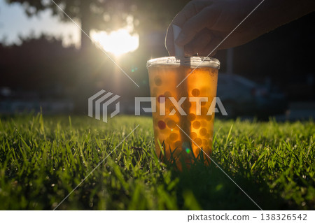 Bubble tea cup on green grass at sunset 138326542