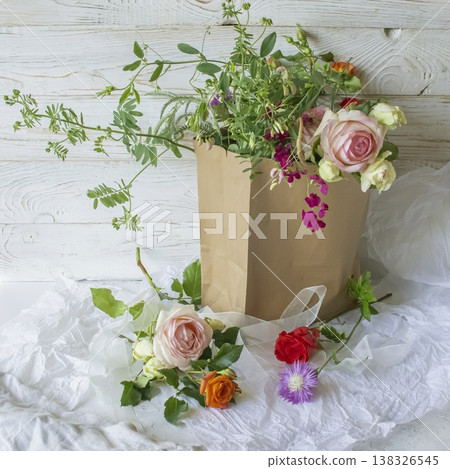 Fresh bouquet of pink roses and wildflowers for gift. Bouquet of colorful flowers in a brown paper bag. Fresh bouquet of pink roses and wildflowers for gift. Bouquet of colorful flowers in a brown paper bag. 138326545