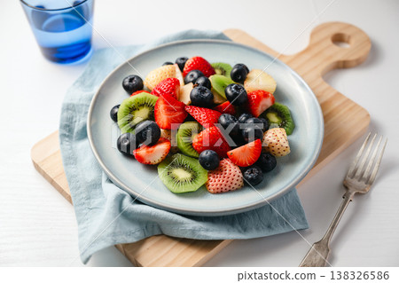 Fresh fruit salad in a plate, kiwi slices, strawberries and blueberries. Healthy food, sweet dessert, top view Fresh fruit salad in a plate, kiwi slices, strawberries and blueberries. Healthy food, sweet dessert, top view 138326586