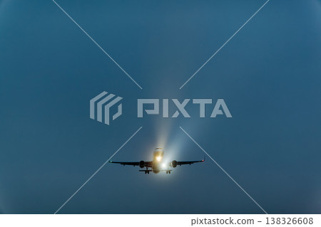 Airplane approaching for landing with landing lights illuminated against a dark, cloudy sky during twilight hours, showcasing aviation technology in action Airplane approaching for landing with landing lights illuminated against a dark, cloudy sky during twilight hours, showcasing aviation technology in action 138326608