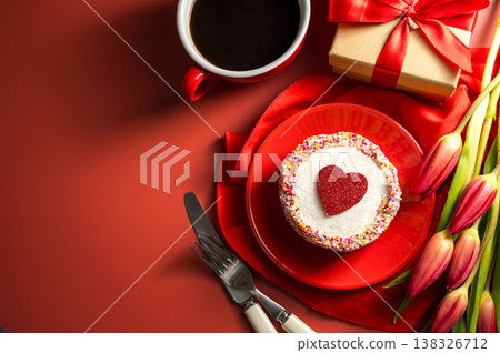 Valentine's Day festive red background. Cake with red heart, cup of coffee, gift box and spring red tulip flower bouquet. Top view Valentine's Day festive red background. Cake with red heart, cup of coffee, gift box and spring red tulip flower bouquet. Top view 138326712