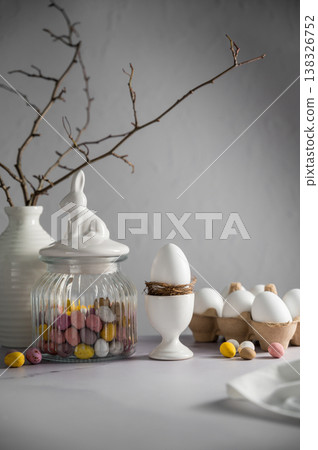 Easter background, table with spring decorations: eggs, candies, twigs in a vase and egg candies. Easter background, table with spring decorations: eggs, candies, twigs in a vase and egg candies. 138326752