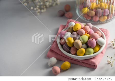 Easter holiday Spring background.Mini chocolate eggs candies in a plate over bright background, copy space Easter holiday Spring background.Mini chocolate eggs candies in a plate over bright background, copy space 138326769