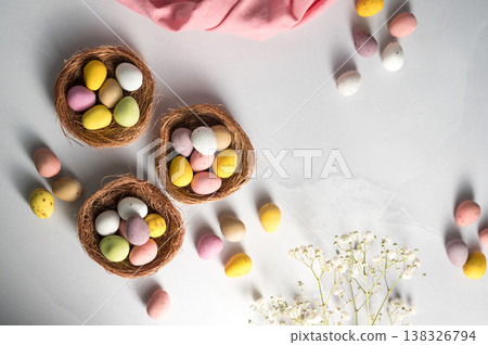 Easter holiday Spring background with mini eggs candy in nests over bright background, copy space 138326794