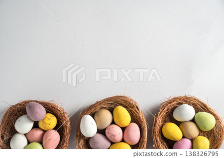 Easter holiday Spring background with mini eggs candy in nests over bright background, copy space Easter holiday Spring background with mini eggs candy in nests over bright background, copy space 138326795