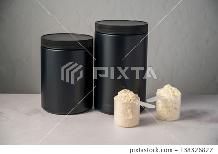 Protein powder in scoops with black protein tubes, jars in background. Body building, muscle growth and food supplement concept 138326827