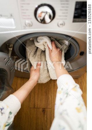 Washing machine at home. Smart appliances. Woman loading the washing machine with towels. Daily chores. Cleaning laundry Washing machine at home. Smart appliances. Woman loading the washing machine with towels. Daily chores. Cleaning laundry 138326888