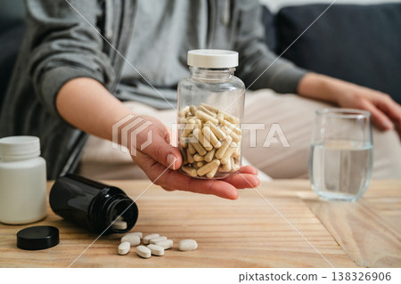 Sickness and health issues. Woman holding a pill bottle at home, healthy care and treatment concept. Sickness and health issues. Woman holding a pill bottle at home, healthy care and treatment concept. 138326906