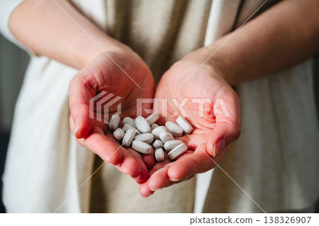 Woman's hands holding a pile of pills and capsules. Prescription medication, treatment sickness concept Woman's hands holding a pile of pills and capsules. Prescription medication, treatment sickness concept 138326907