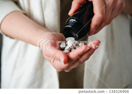 Woman pouring a pile of pills, capsules from a bottle in hand. Prescription medication, treatment sickness concept 138326908
