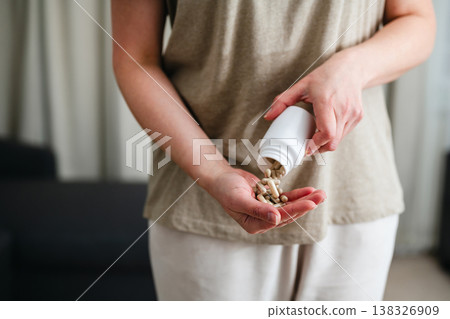 Woman pouring a pile of pills, capsules from a bottle in hand. Prescription medication, treatment sickness concept 138326909