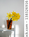 Spring floral background. Yellow fresh Daffodils in orange glass vase, over white background with copy space. Easter abstract mockup 138326916