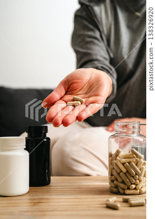 Food supplements and vitamins. Woman holding a pill capsules with pill bottles at home, healthy care concept. 138326920