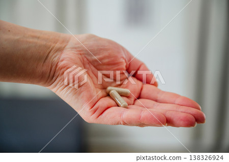 Woman hand closeup, holding capsules pills. Prescription medication, treatment sickness, seasonal cold flu concept Woman hand closeup, holding capsules pills. Prescription medication, treatment sickness, seasonal cold flu concept 138326924