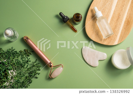 Rose quartz gua sha tool and face massage roller on green background, beauty abstract photo. Top view Rose quartz gua sha tool and face massage roller on green background, beauty abstract photo. Top view 138326992