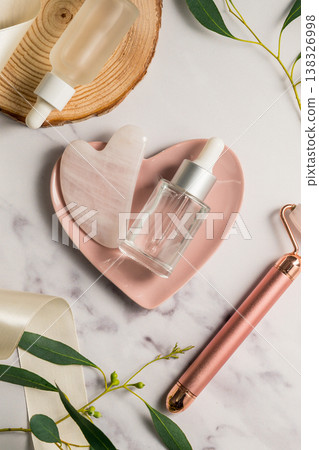 Rose quartz gua sha tool and oil bottle and face massage roller, beauty abstract photo. Top view Rose quartz gua sha tool and oil bottle and face massage roller, beauty abstract photo. Top view 138326998