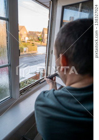 Spring home cleaning. Man vacuums plastic window frame. Spring home cleaning. Man vacuums plastic window frame. 138327024
