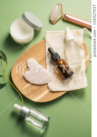 Rose quartz gua sha tool and face massage roller on green background, beauty abstract photo. Top view Rose quartz gua sha tool and face massage roller on green background, beauty abstract photo. Top view 138327037