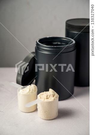 Protein powder in scoops with black protein tubes, jars in background. Body building, muscle growth and food supplement concept 138327040