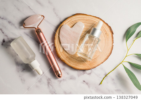 Rose quartz gua sha tool and face massage roller on wooden tray, beauty abstract photo. Top view 138327049